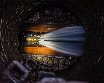 Blick von oben in einen Abwasserkanal beim Spülvorgang