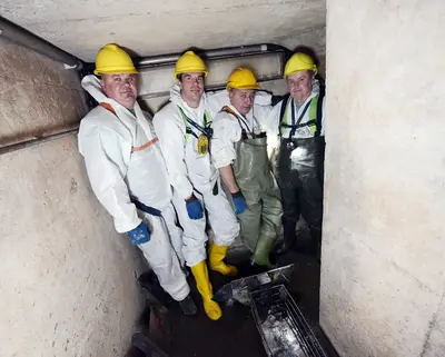 vier Mitarbeiter von SWM aus dem Bereich Abwasser stehen im Abwasser-Kanal